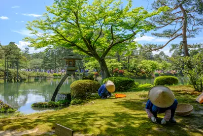Jardinero japonés cerca de la linterna Toro en Kenrokuen, un jardín japonés en Kanazawa, prefectura de Ishikawa, Japón.
