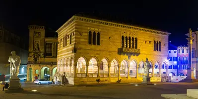 Vista nocturna de la plaza principal de Udine Piazza liberta con el ayuntamiento iluminado
